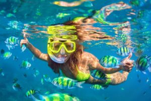 Young woman snorkeling in crystal clear water over a coral reef in Cancun