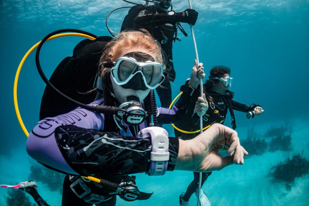 alt="Advanced diver performing a safety stop in clear waters while checking dive computer during SSI course in Cancun"