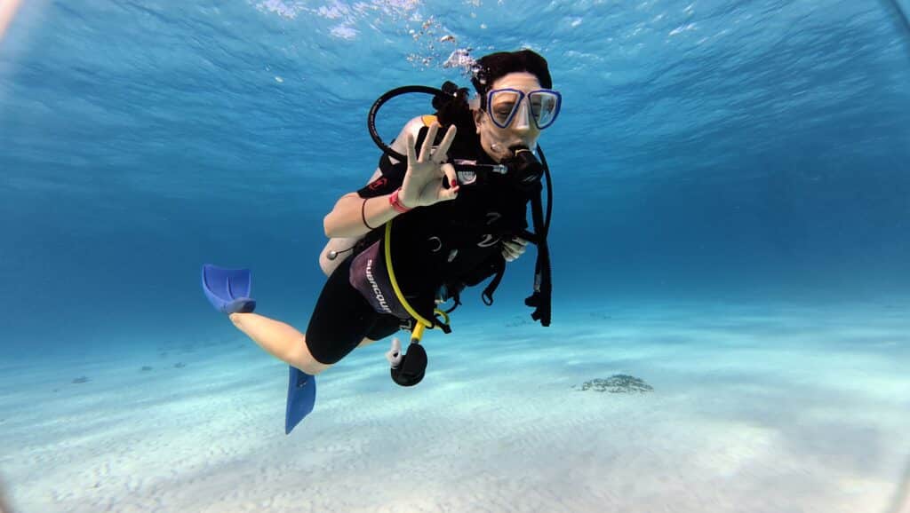 Female scuba diver giving OK sign underwater in Cancun coral reef