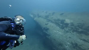Diver beside the hull of the C-55 Juan de la Barrera shipwreck in Cancún — Vision Oceanos